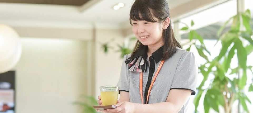 女性スタッフが笑顔でお茶を運んでいる写真
